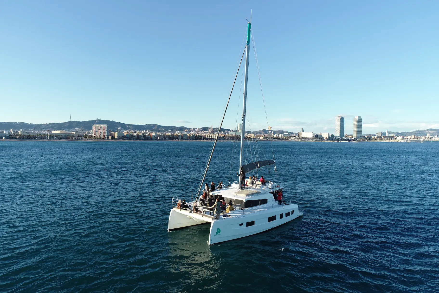 Catamarán CAT35 Luxury navegando frente al skyline de Barcelona con pasajeros a bordo